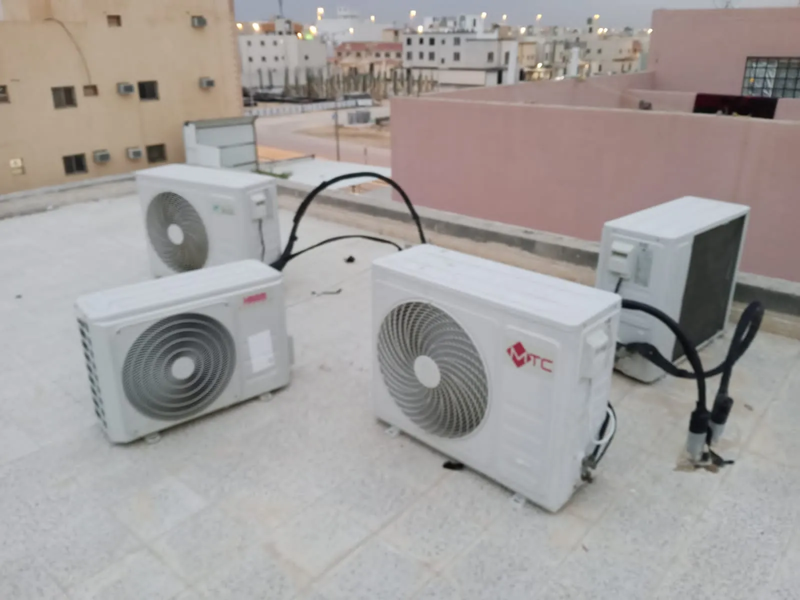 ثلاث وحدات تكييف خارجية على سطح منزل بجدران وردية