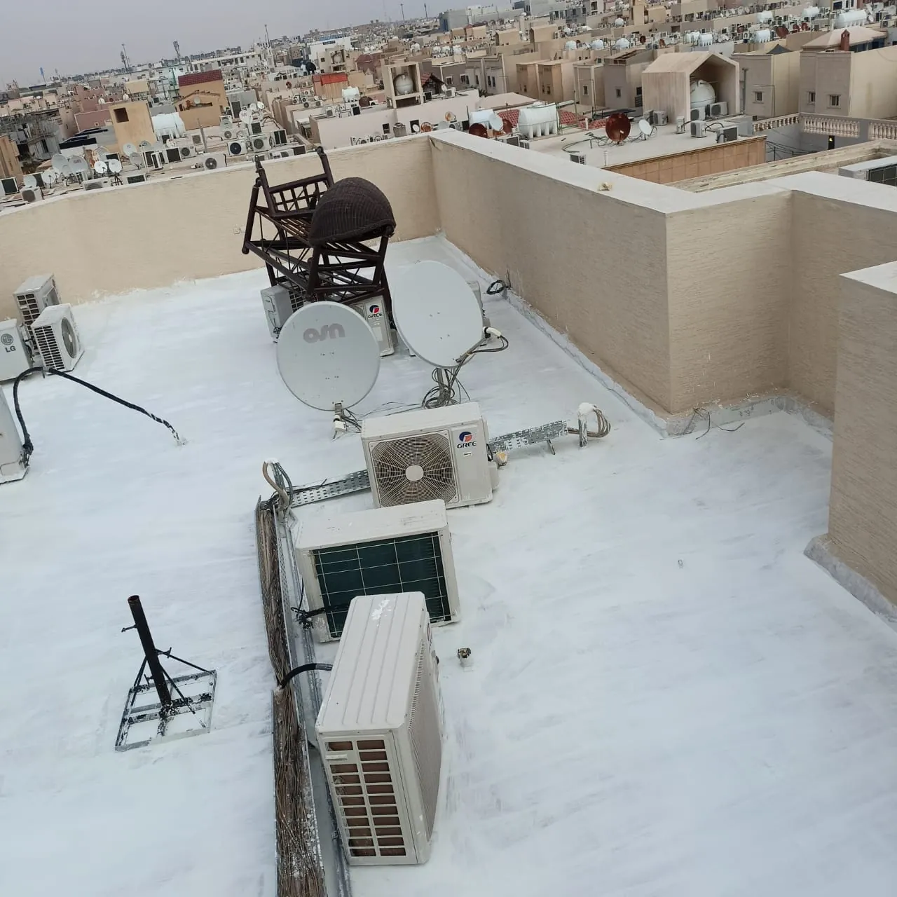 سطح مبنى بأرضية بيضاء وعليه وحدات تكييف خارجية وأطباق استقبال